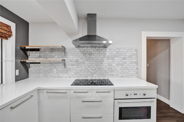 kitchen with black electric stovetop, oven, wall chimney exhaust hood, white cabinets, and dark hardwood / wood-style floors