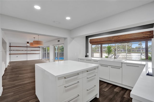 kitchen with a sink, a healthy amount of sunlight, light countertops, white cabinets, and dark wood-type flooring