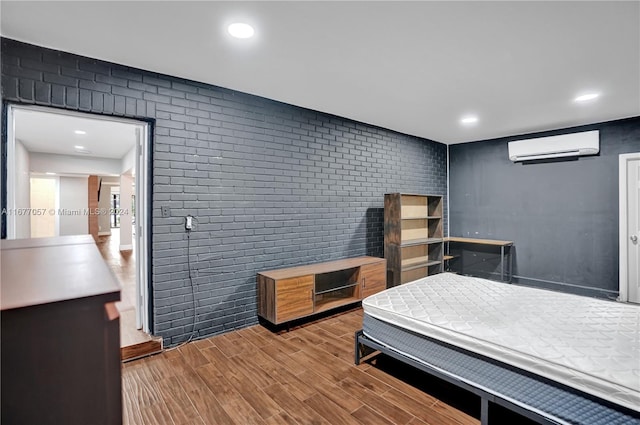 bedroom featuring an AC wall unit, wood-type flooring, and brick wall