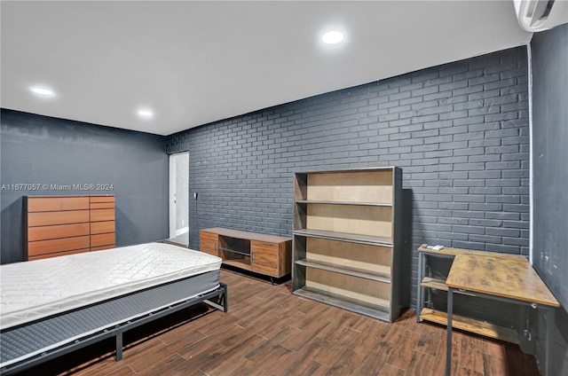 bedroom featuring brick wall and dark hardwood / wood-style floors