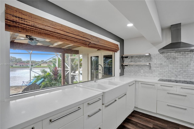 kitchen with open shelves, decorative backsplash, light countertops, and wall chimney range hood