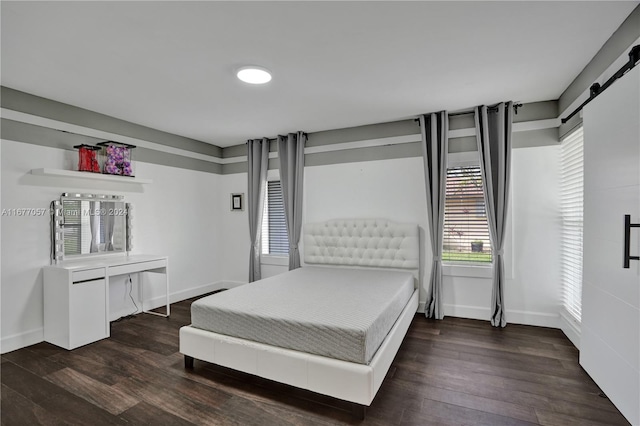 bedroom with a barn door and dark hardwood / wood-style floors