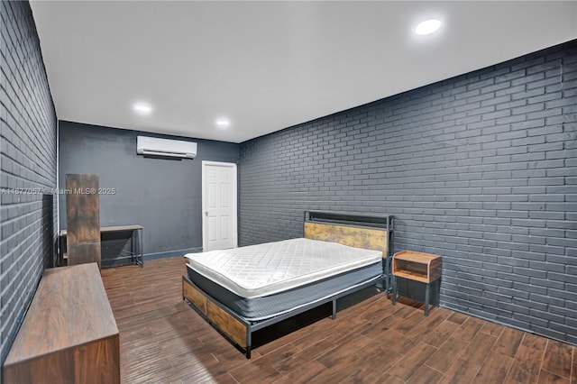 bedroom featuring a wall mounted AC, wood finished floors, and brick wall