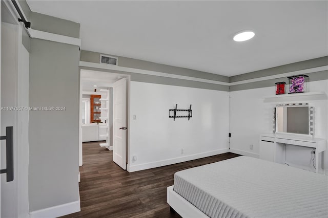 bedroom featuring dark wood-type flooring and a barn door