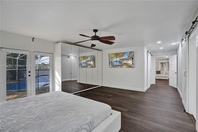 bedroom featuring access to exterior, a barn door, dark hardwood / wood-style floors, and ceiling fan