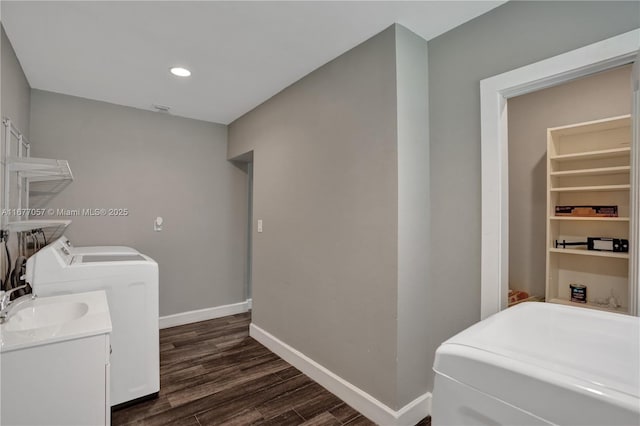 laundry area with washing machine and clothes dryer, a sink, dark wood finished floors, baseboards, and laundry area
