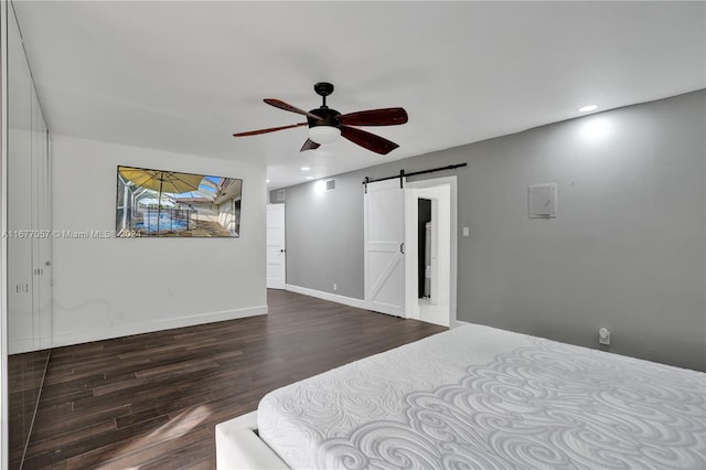 bedroom with a barn door, dark wood-type flooring, and ceiling fan