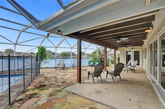 view of patio / terrace with a water view, ceiling fan, and glass enclosure