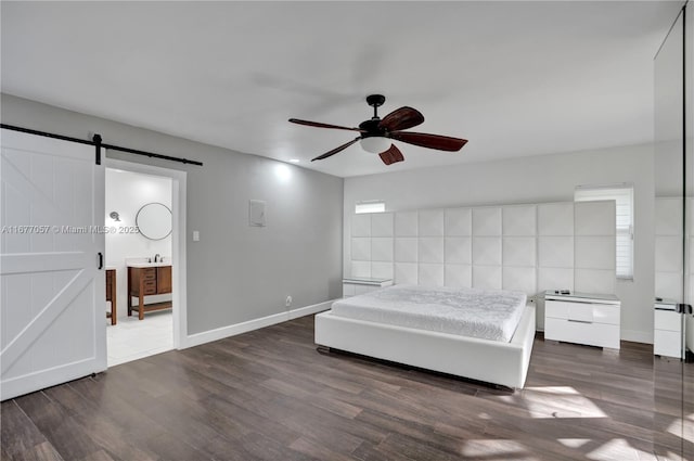 bedroom with a barn door, a ceiling fan, wood finished floors, a sink, and baseboards