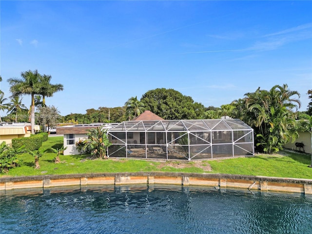 rear view of property with a water view, glass enclosure, and a yard