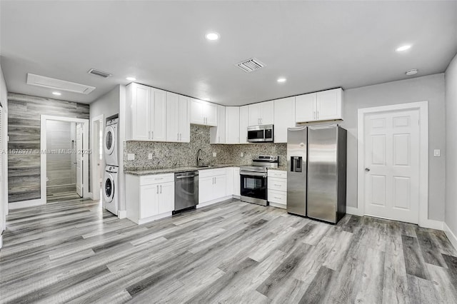 kitchen featuring stacked washing maching and dryer, light wood-type flooring, visible vents, and stainless steel appliances