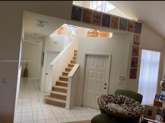 entrance foyer featuring light tile patterned floors, a textured ceiling, and lofted ceiling