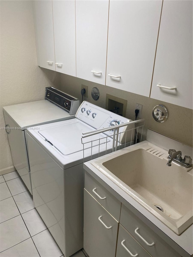 laundry room with cabinets, sink, light tile patterned floors, and washer and dryer