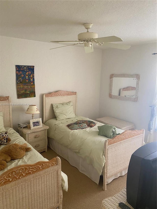 carpeted bedroom featuring ceiling fan and a textured ceiling