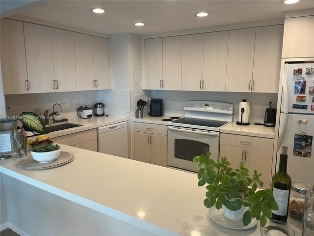 kitchen with decorative backsplash, kitchen peninsula, sink, white cabinets, and white appliances