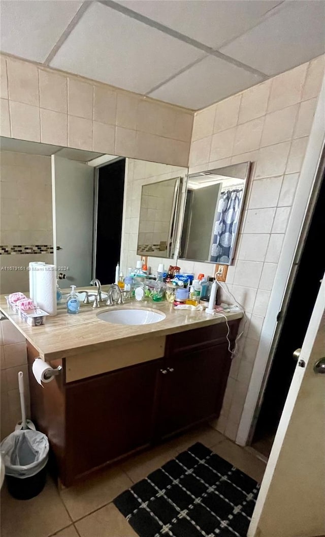 bathroom featuring tile walls, vanity, a paneled ceiling, and tile patterned flooring