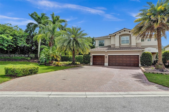 mediterranean / spanish house featuring a garage and a front lawn