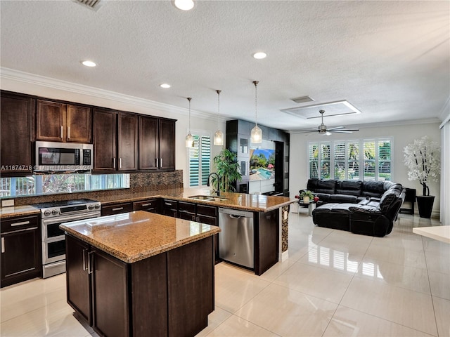 kitchen featuring appliances with stainless steel finishes, a center island, decorative light fixtures, and sink