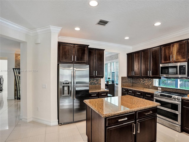 kitchen with a kitchen island, appliances with stainless steel finishes, dark brown cabinets, and backsplash