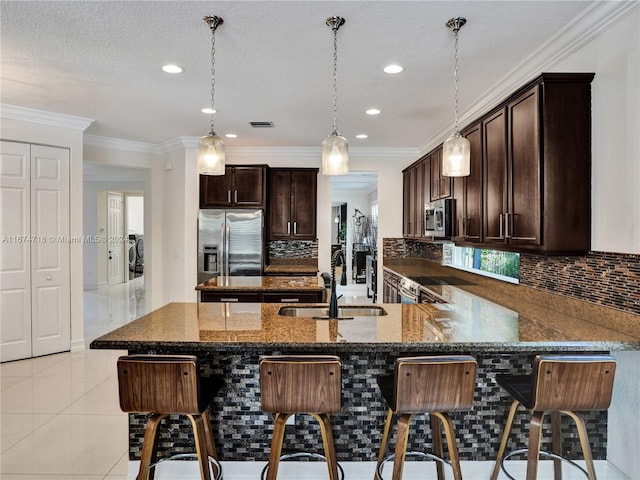 kitchen with tasteful backsplash, appliances with stainless steel finishes, a kitchen bar, ornamental molding, and sink