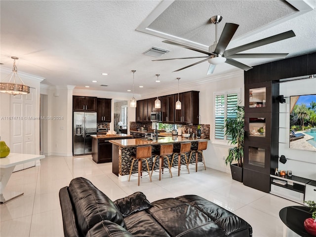 kitchen with tasteful backsplash, hanging light fixtures, light tile patterned floors, appliances with stainless steel finishes, and dark brown cabinetry