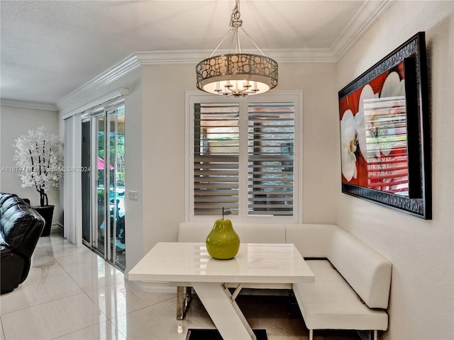 tiled dining space featuring ornamental molding, breakfast area, and an inviting chandelier