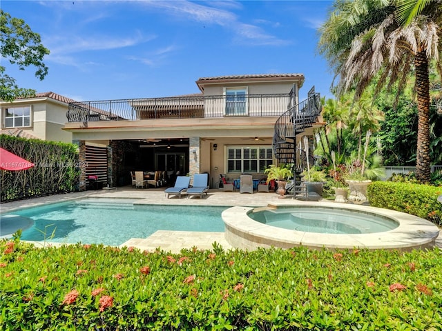 rear view of house with a balcony, a swimming pool with hot tub, a patio, and ceiling fan