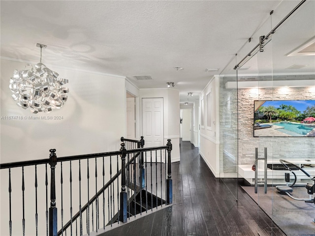 hall featuring a textured ceiling, crown molding, a notable chandelier, and dark hardwood / wood-style floors