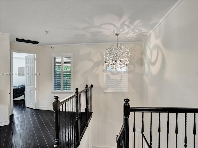 stairs with crown molding, a textured ceiling, wood-type flooring, and an inviting chandelier