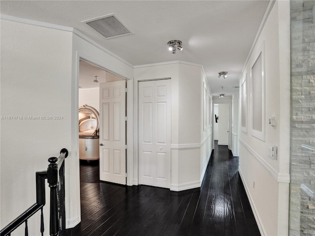 hallway with crown molding, a textured ceiling, and dark wood-type flooring