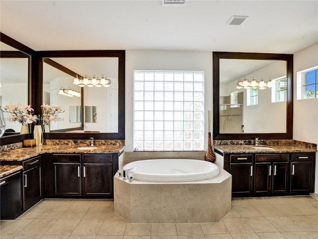 bathroom featuring vanity, tile patterned floors, a wealth of natural light, and tiled tub