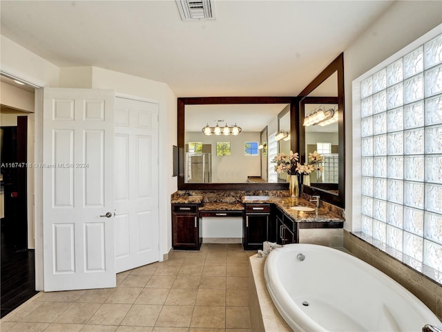 bathroom featuring vanity, a healthy amount of sunlight, tile patterned flooring, and tiled tub