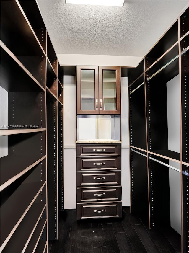 walk in closet with dark hardwood / wood-style floors