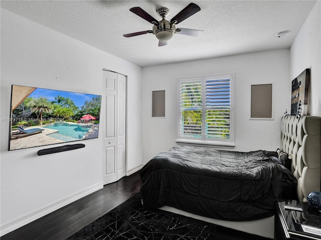 bedroom featuring a closet, dark hardwood / wood-style floors, a textured ceiling, and ceiling fan