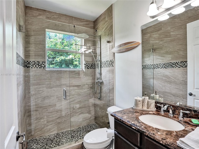 bathroom featuring toilet, vanity, and a shower with door