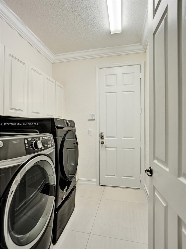 washroom with light tile patterned floors, ornamental molding, cabinets, washing machine and dryer, and a textured ceiling