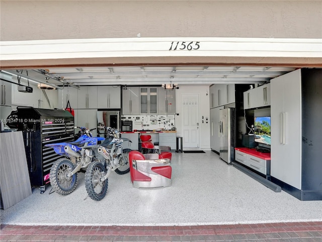 garage featuring stainless steel fridge and a garage door opener