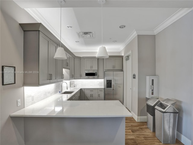 kitchen with kitchen peninsula, hanging light fixtures, dark hardwood / wood-style flooring, gray cabinets, and stainless steel appliances