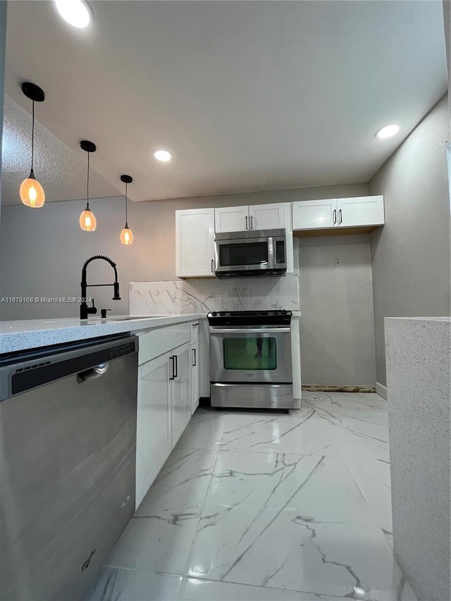 kitchen featuring appliances with stainless steel finishes, white cabinetry, sink, and hanging light fixtures