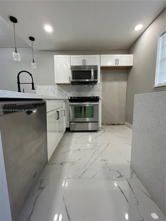 kitchen featuring white cabinets, pendant lighting, marble finish floor, and appliances with stainless steel finishes