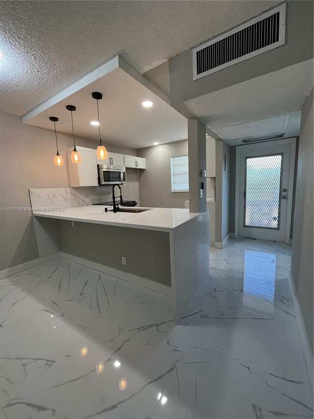 kitchen featuring stainless steel microwave, marble finish floor, baseboards, and white cabinetry
