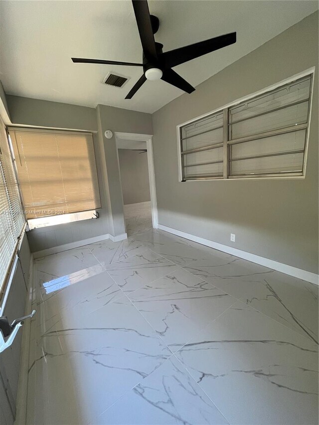 spare room featuring marble finish floor, baseboards, ceiling fan, and visible vents