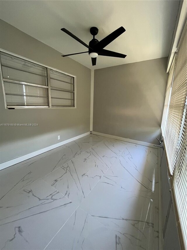 unfurnished room with marble finish floor, baseboards, and a ceiling fan