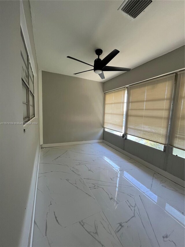 spare room with marble finish floor, baseboards, a ceiling fan, and visible vents