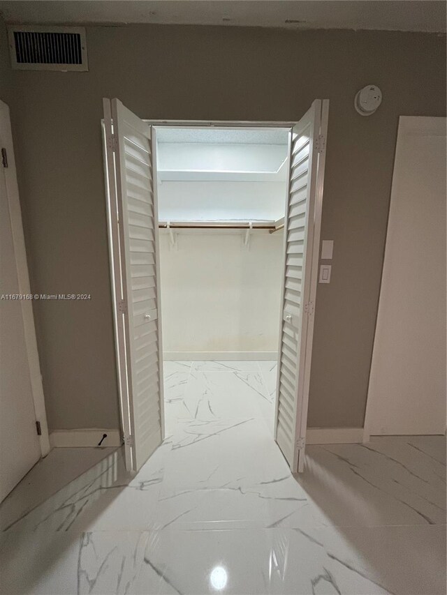 hallway with marble finish floor, baseboards, and visible vents