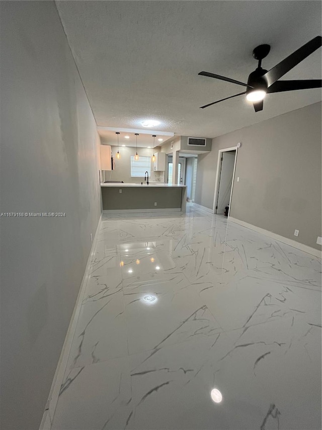 spare room with a textured ceiling, sink, and ceiling fan