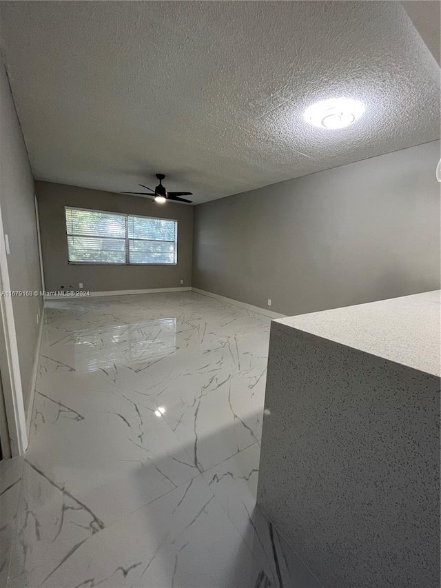 empty room featuring ceiling fan and a textured ceiling