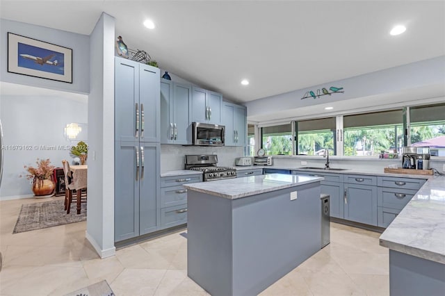 kitchen featuring a wealth of natural light, sink, light stone countertops, and stainless steel appliances