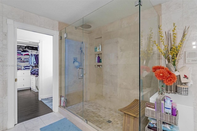 bathroom with a shower with door, tile walls, a textured ceiling, and hardwood / wood-style flooring