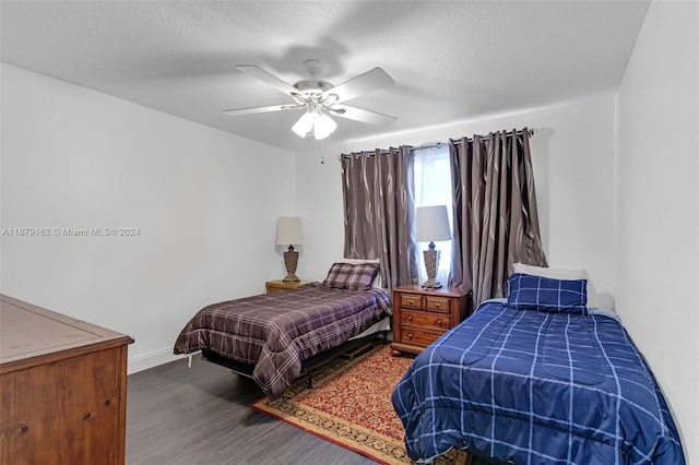 bedroom with a textured ceiling, wood-type flooring, and ceiling fan